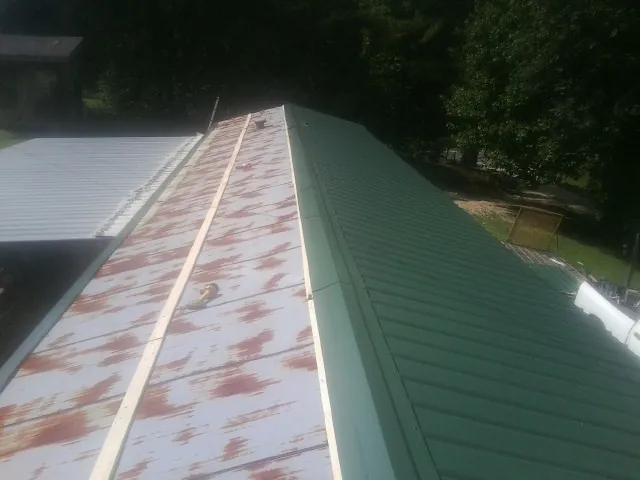 Old rusted panels beside newly installed green metal roofing — Wind Damage Roof Repair by Roofing Brothers in Beach Haven