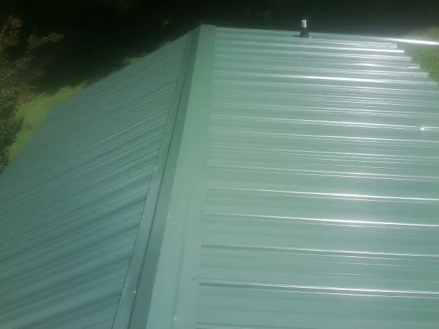 New green metal panels meeting at the ridge of a roof — Flat Roof Repair work by our crew in Beach Haven