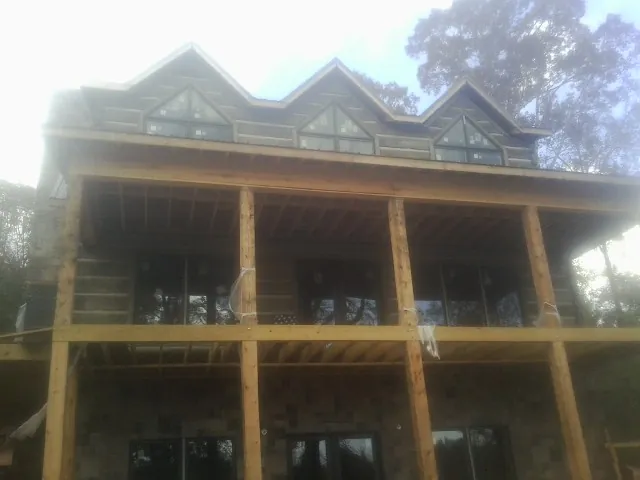 Dormers and porch framing on a large log home under construction — Roof Coating work by our crew in Beach Haven