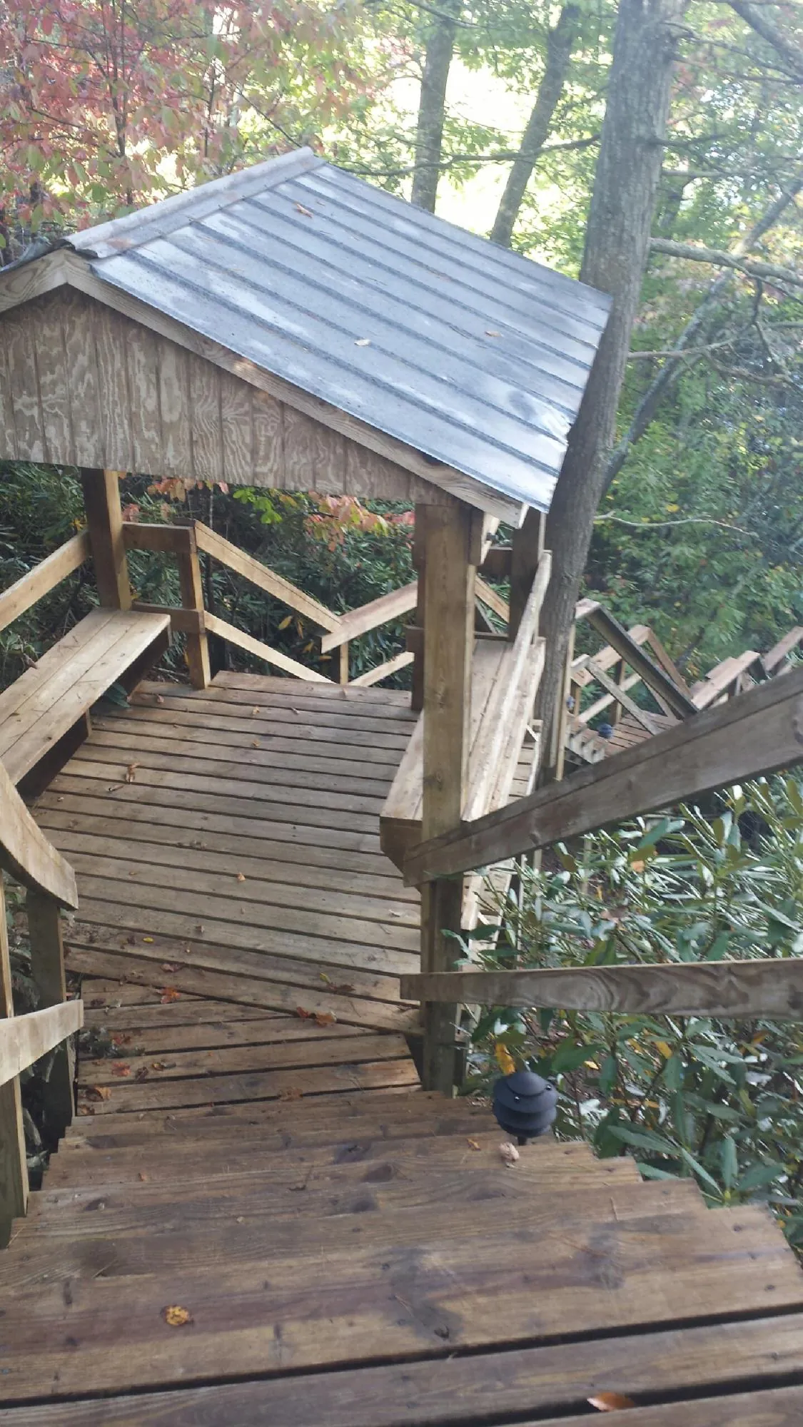 Metal roofed shelter over wooden steps on a wooded walkway — Skylight Repair & Installation work by our crew in Beach Haven