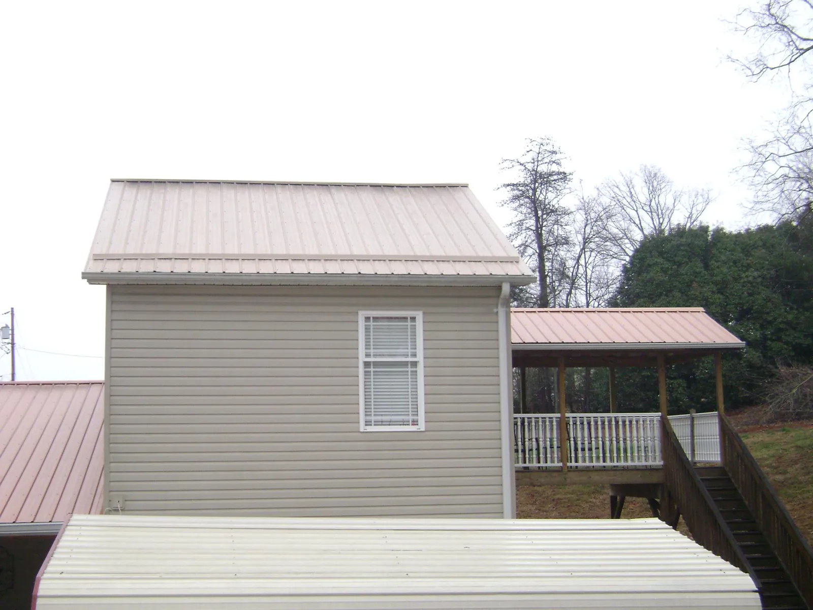 Tan metal roofs on a two story addition and attached porch, from a Roof Replacement job in Beach Haven