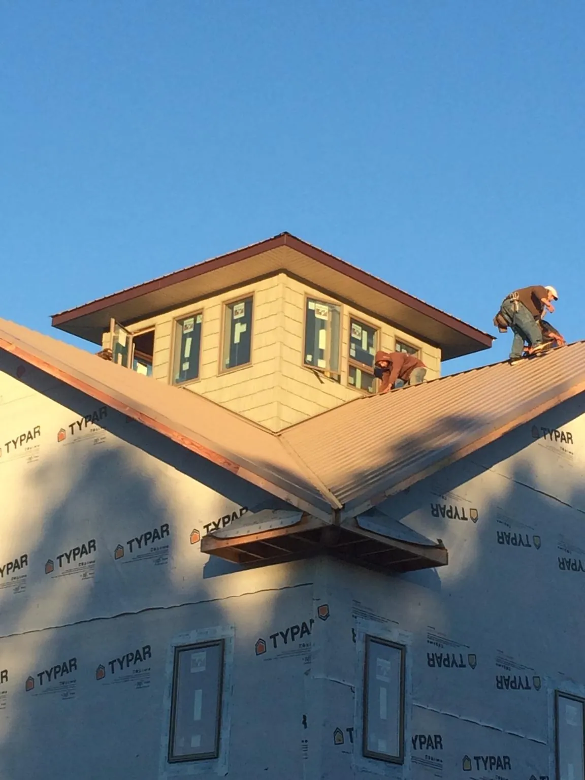 Roofers working around a rooftop cupola on a new metal roof at sunset — Roof Waterproofing in Beach Haven by Roofing Brothers